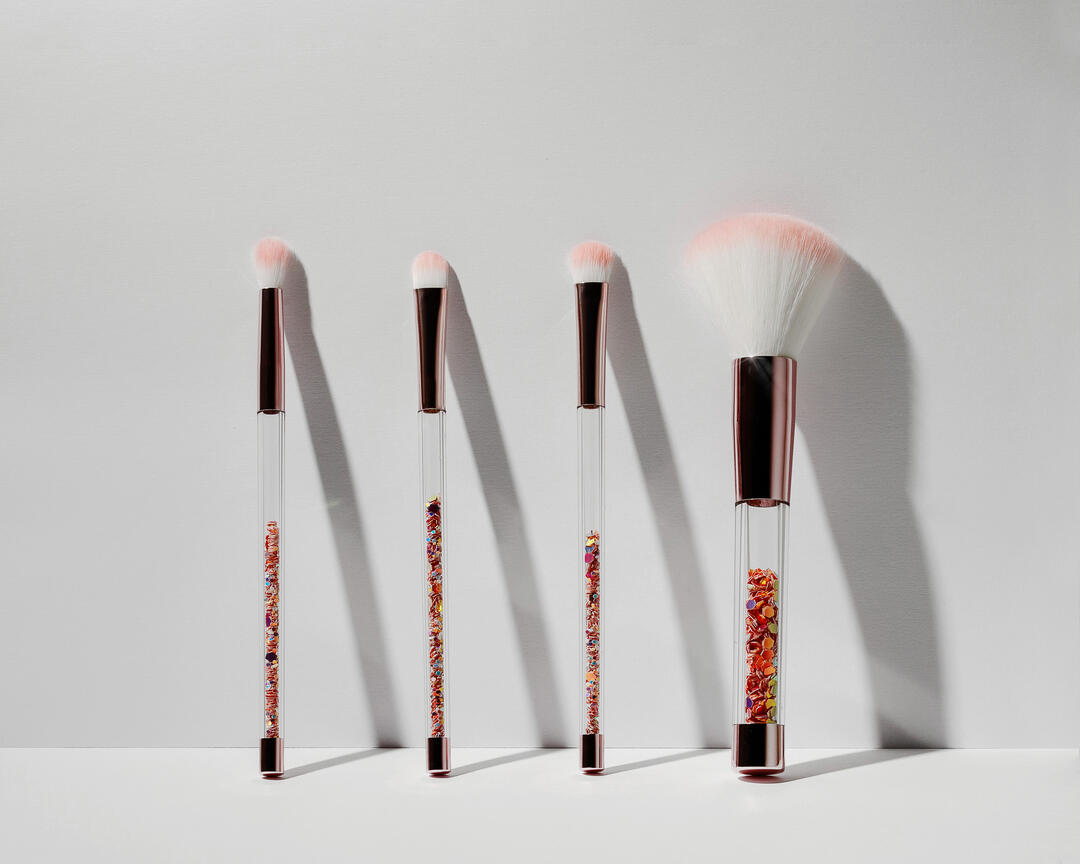 The brushes stand on a light background. The brushes stand on a light background. A harsh light shines on them. The brushes have transparent handles.