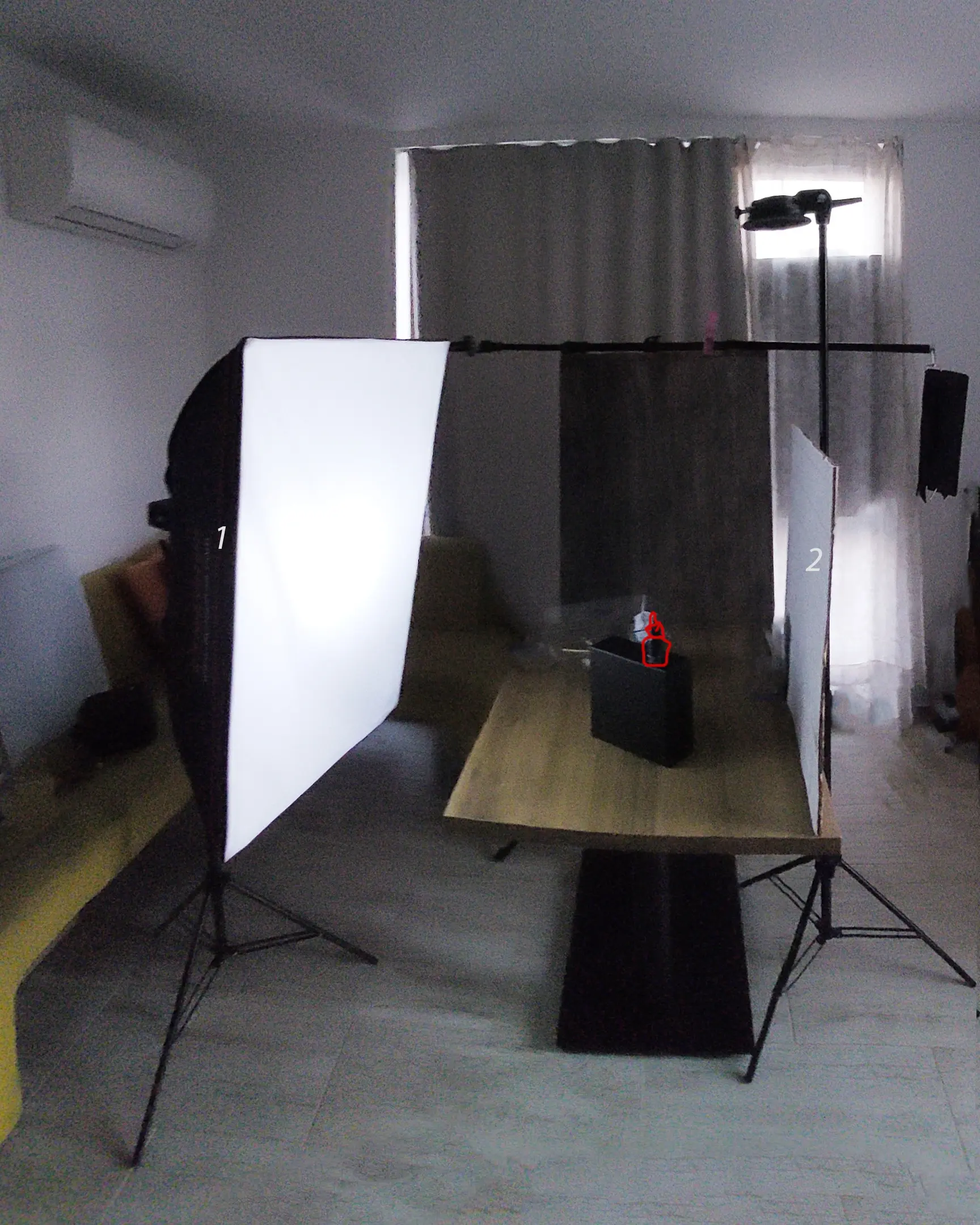 Light schema 1 for the photo with one light and fire. The picture shows the lighting scheme. There is a flash with a strip box in the room. There is a black box on the table with the subject on it. To the right of the object is a reflector. It has the number 2 written on it.