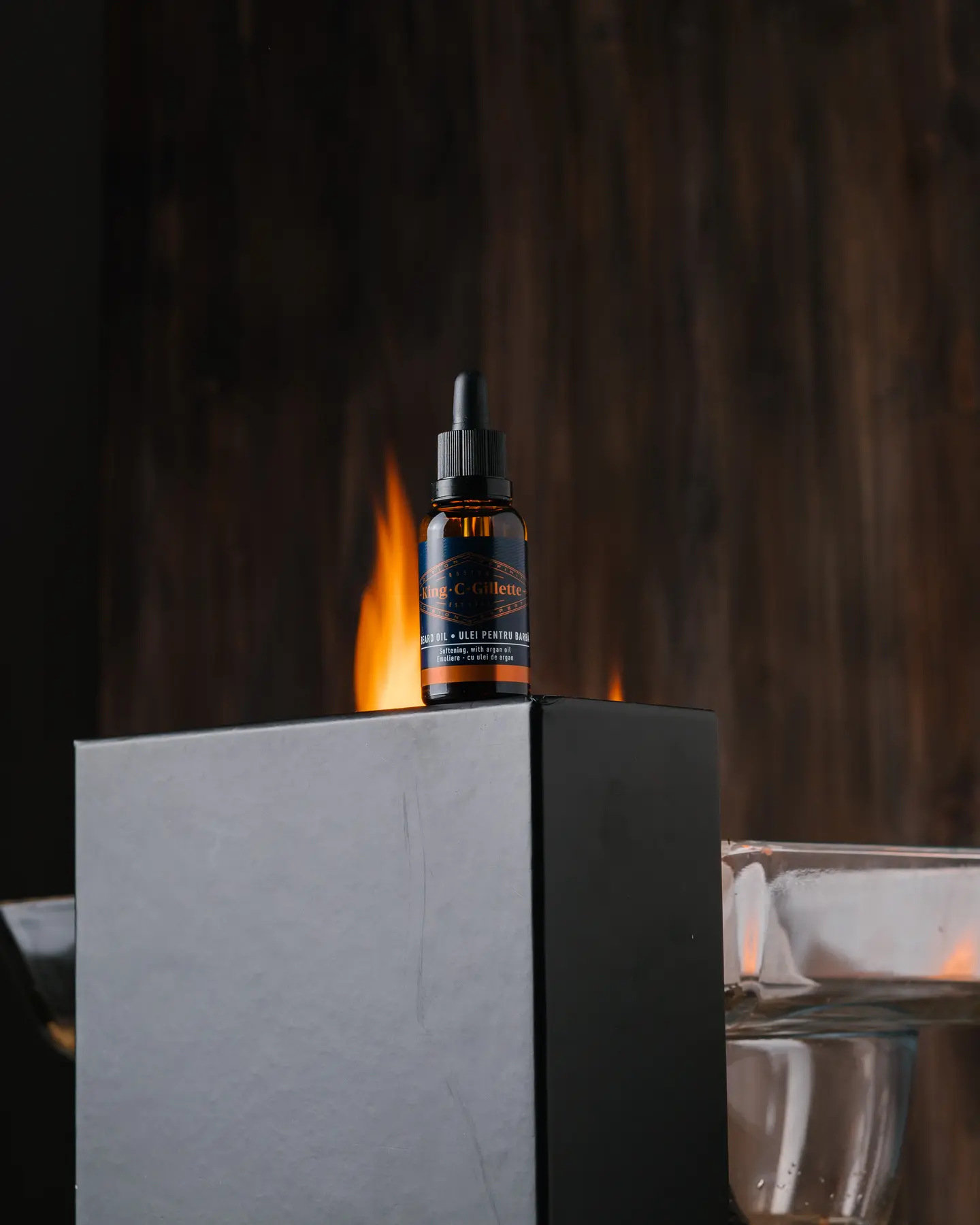 Left Fire. The photo that was taken as the source of the fire from the left side. On the black box is a bottle of King C Gillette of beard oil. It is lit from the left side. A wooden background is visible behind the jar and box.