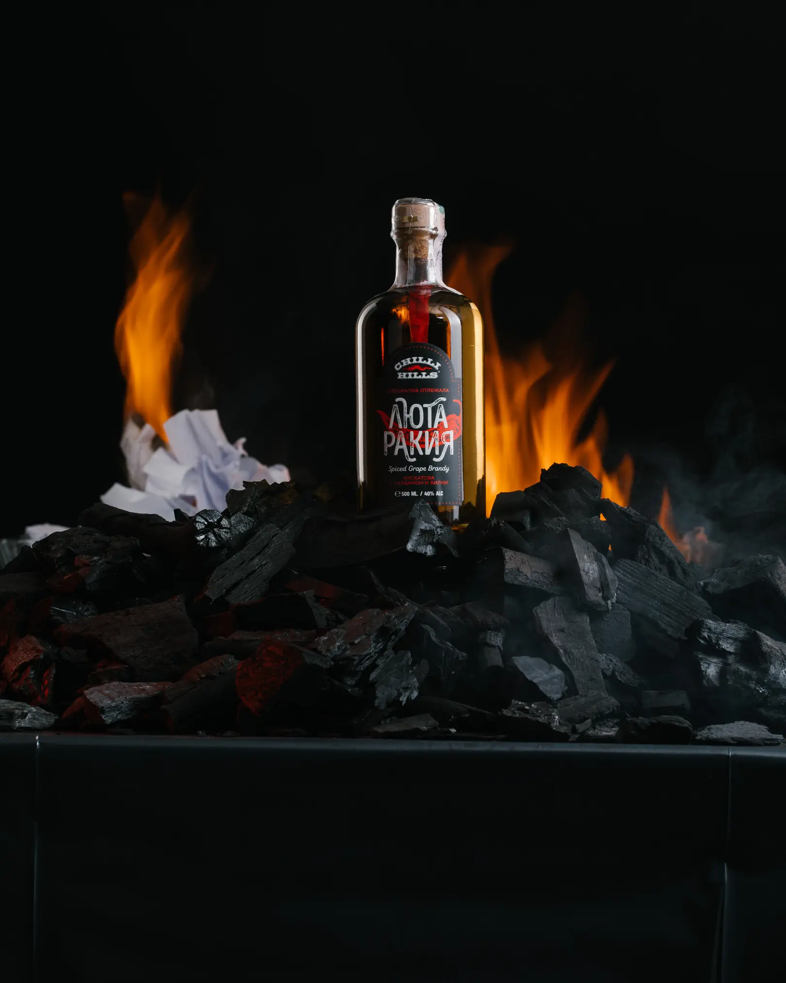 Light Schema 3 Result 2. The photo shows the result of shooting a bottle according to the light scheme shown 1 frame earlier. The viewer sees the label of the bottle. Also, viewers can see the fire in the background.