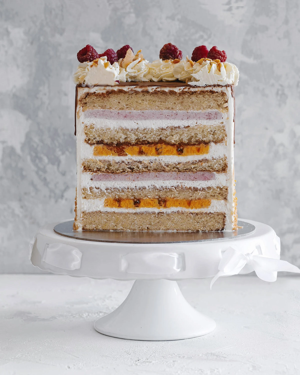 Сake on a ceramic cake stand.  On a light background, there is a cake on a ceramic cake stand. Layers of cake and cream are visible.