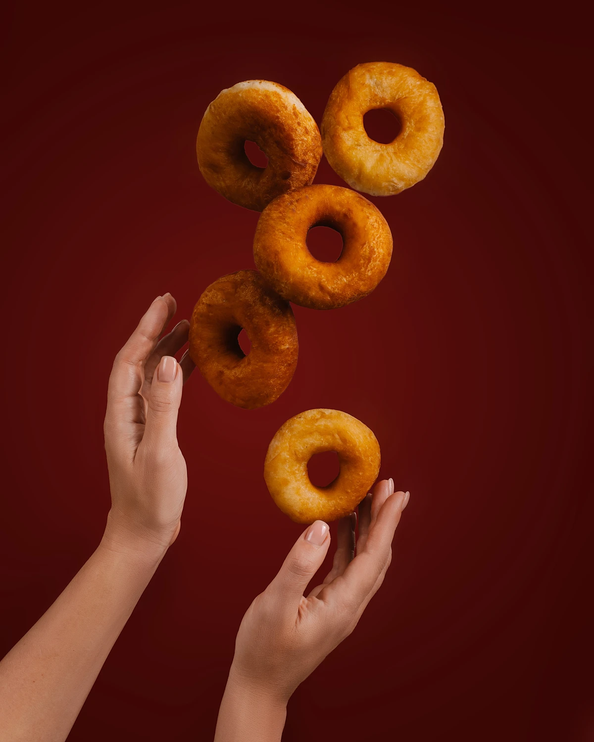Donuts hung in the air The photo shows female hands and donuts flying in the air above them.