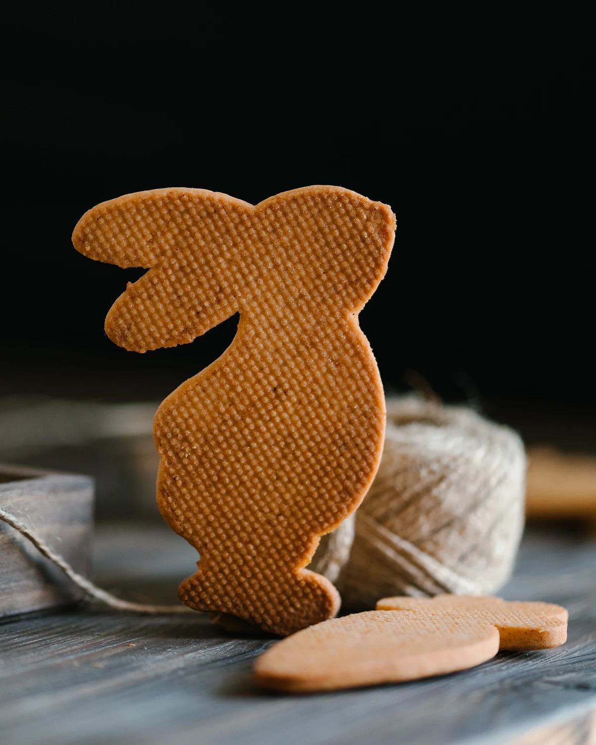 Shortbread in the shape of a hare. A shortbread cookie in the shape of a hare stands on a wooden table. Behind is a roll of thread.