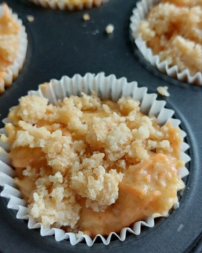 The cupcakes are ready for further baking. The cake batter is in a baking dish and sprinkled with crumble. The cupcakes are ready for further baking.