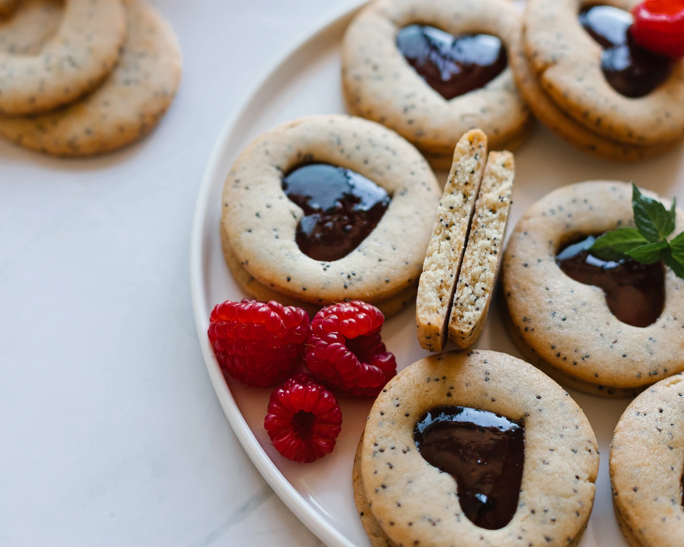 Poppy-seed cookies lie on a ceramic plate.  Poppy-seed cookies lie on a ceramic plate. Some of the cookies are broken and their texture is visible.
There are also raspberries on the plate - as the cookies are layered with raspberry jam.