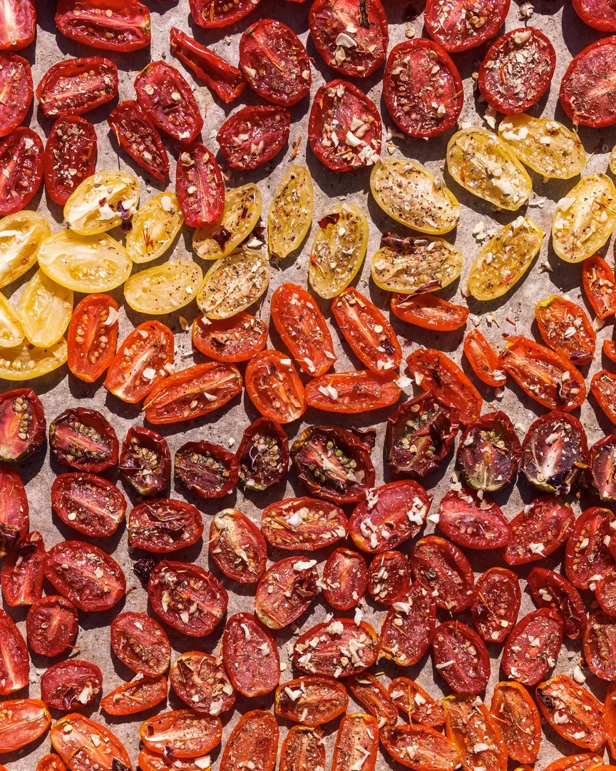 Dried tomatoes. Halves of tomatoes lie under bright sunlight. Tomatoes are already dried, and spices are visible on them