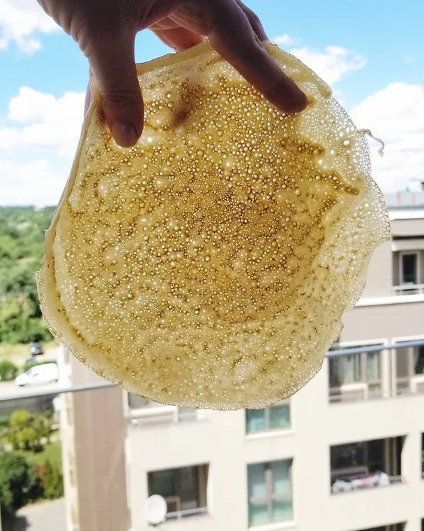 Woman's hand holding a pancake. A woman's hand holds a pancake to show how lacy and thin it is.