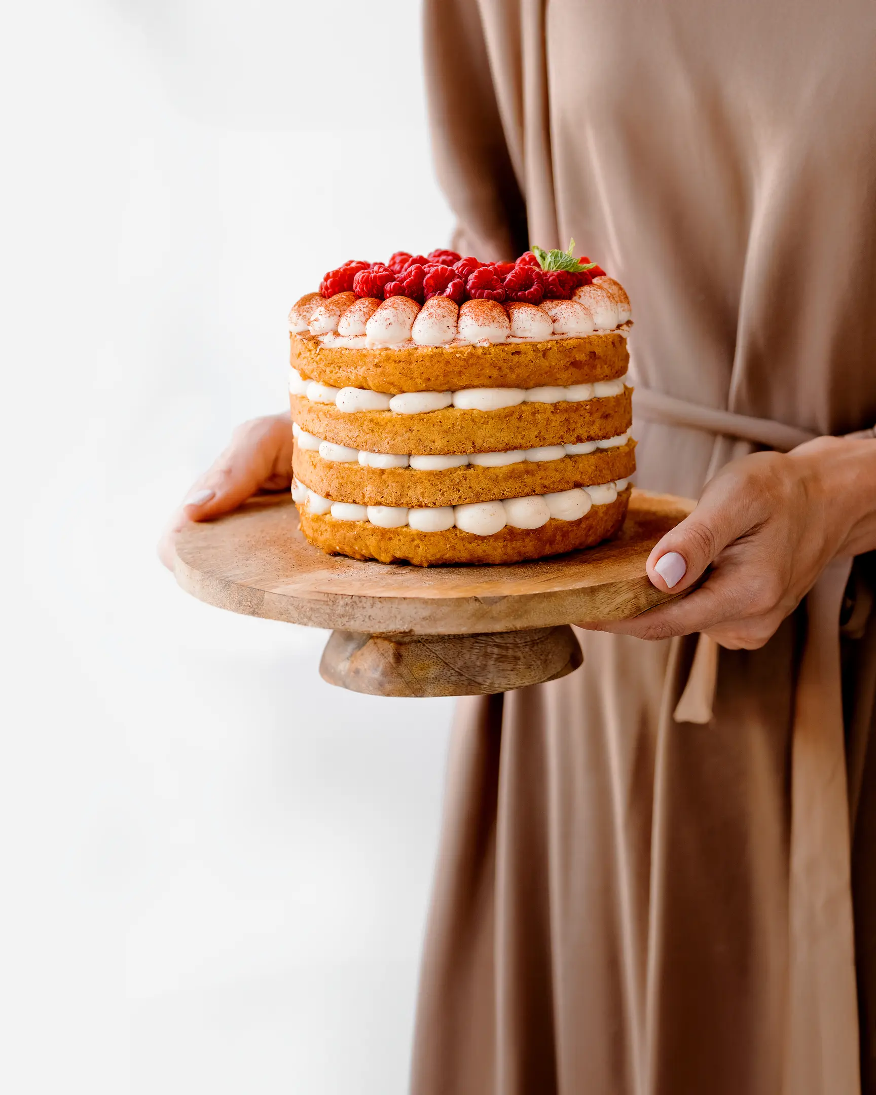 A woman holding plate with cake in her hands. A woman holding a plate with cake in her hands. Cake decorated with strawberries