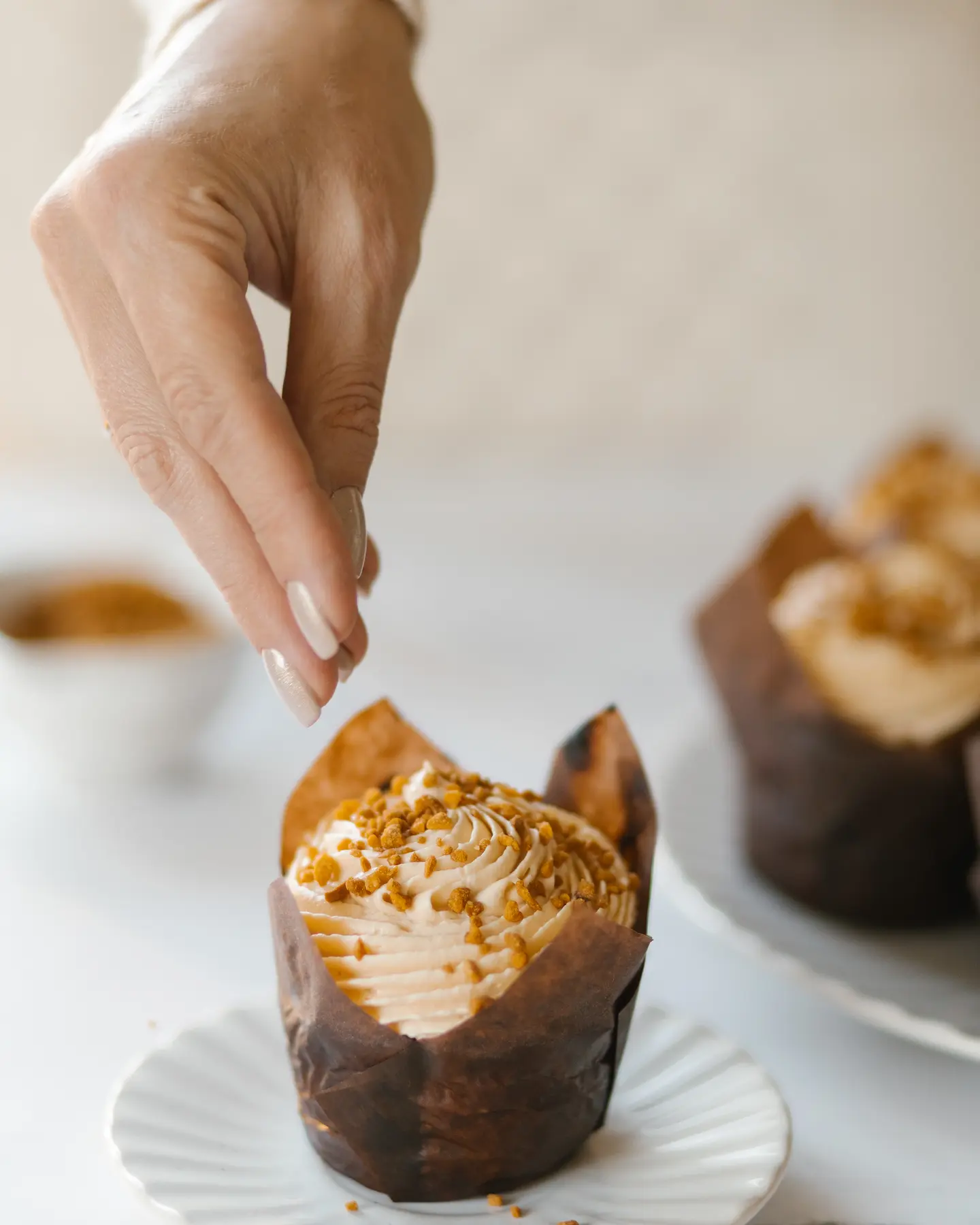 A woman sprinkles from her hand the nuts on the muffin. A woman sprinkles from her hand the nuts on the muffin.