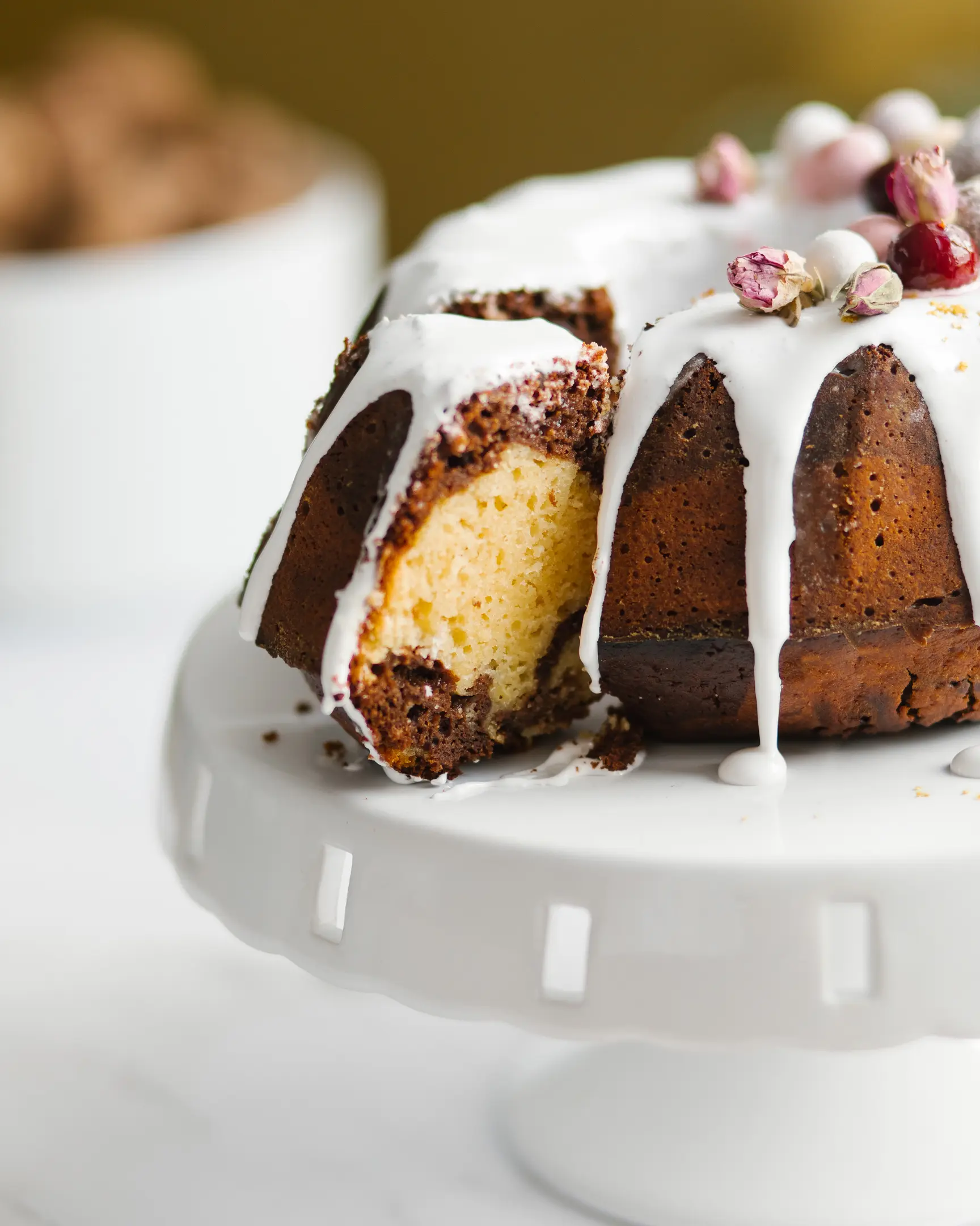 The cake is on the cake stand. The cupcake is on the cake stand. The cake is cut. The chocolate and orange portions of the cake are visible. Cake decorated with chocolate eggs.  