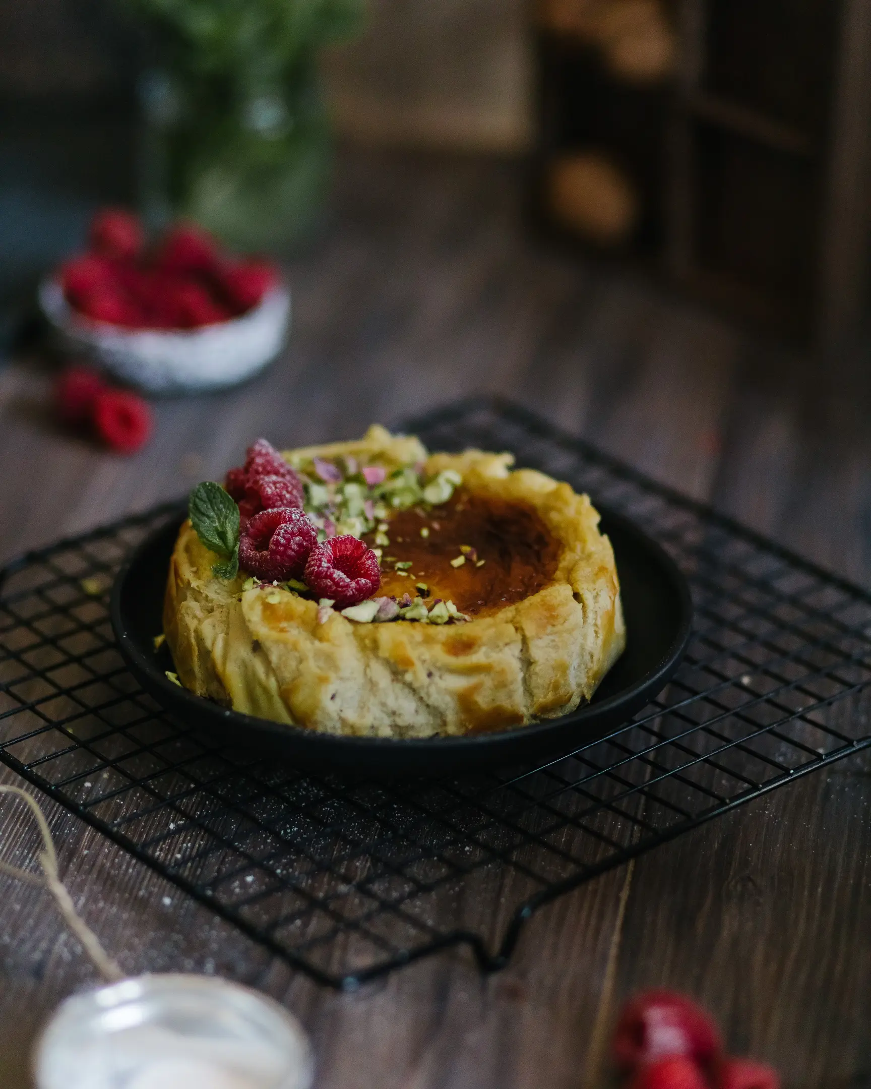 Gorgeous pistachio cheesecake stands on the table. Gorgeous pistachio cheesecake stands on the table. It is decorated with raspberries.