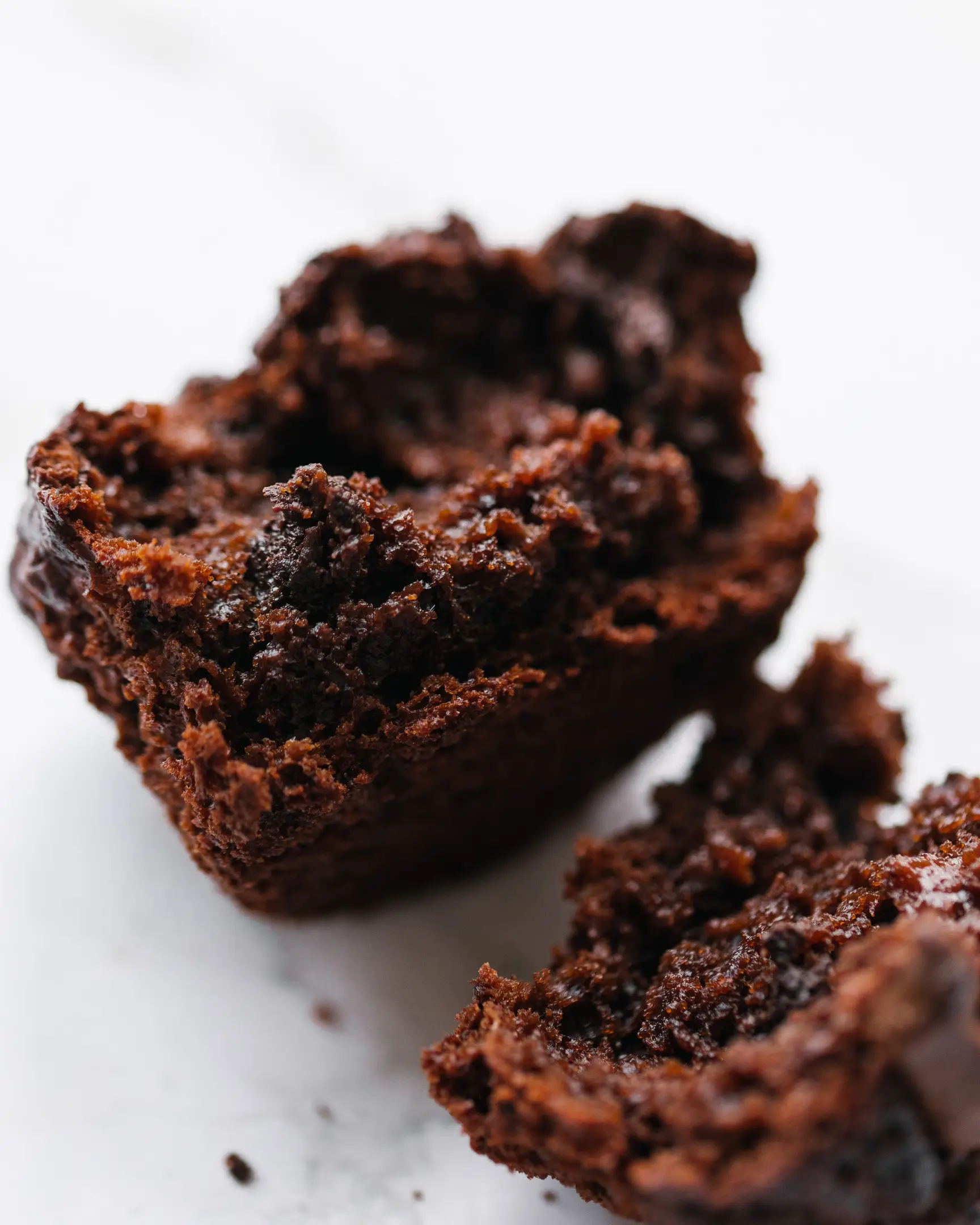 The chocolate-apple cupcake was cut.  The cupcake is cut. Delicate texture is visible. The wet crumb of the dough attracts the viewer.