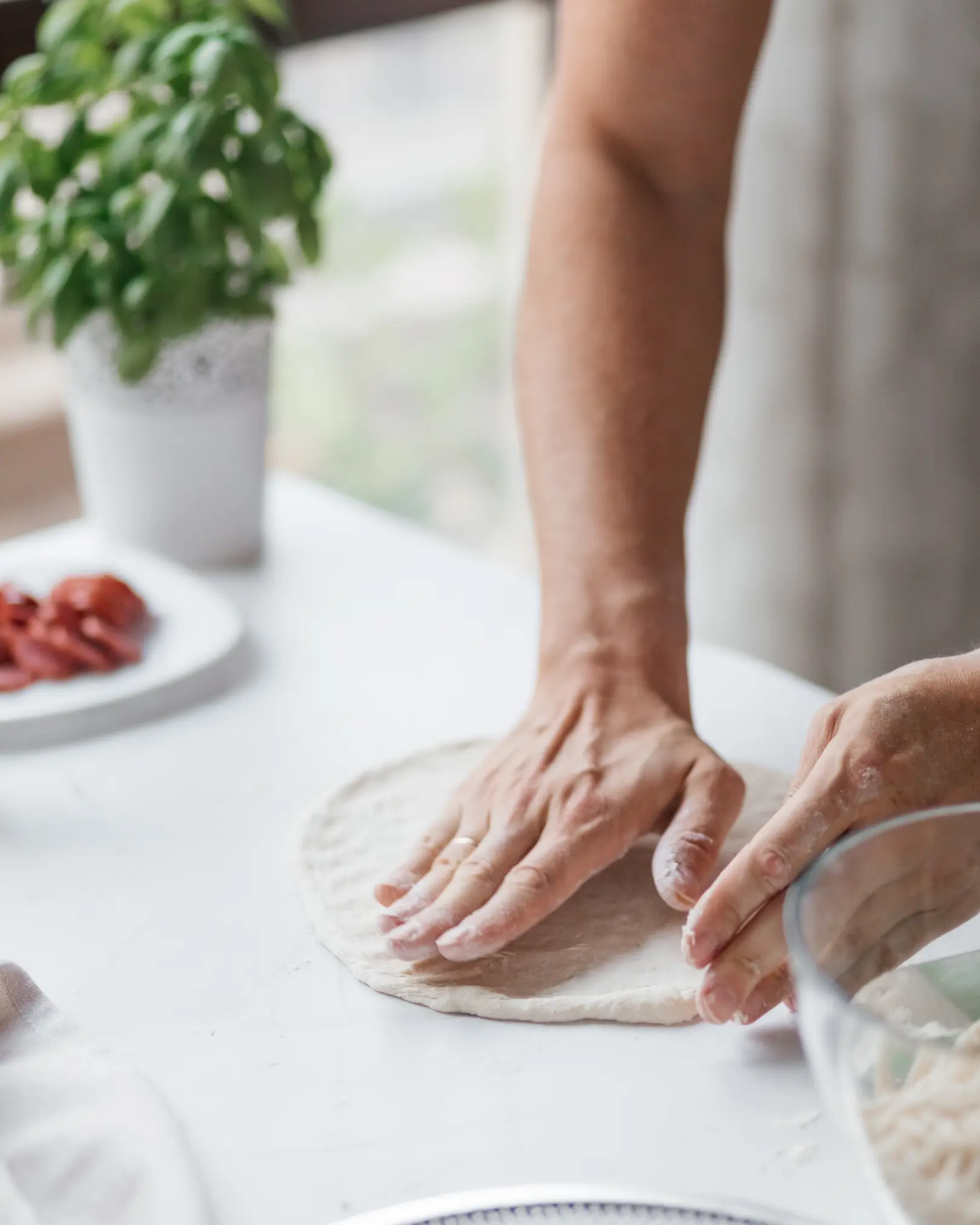 A man stretches pizza dough on the table. A man stretches pizza dough on the table. The process of making pizza.