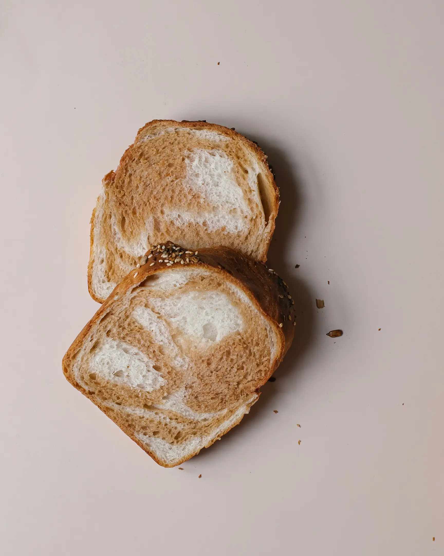 2 филийки хляб лежат на светъл фон. 2 филийки хляб лежат на светъл фон. Нарязват се. видима текстура