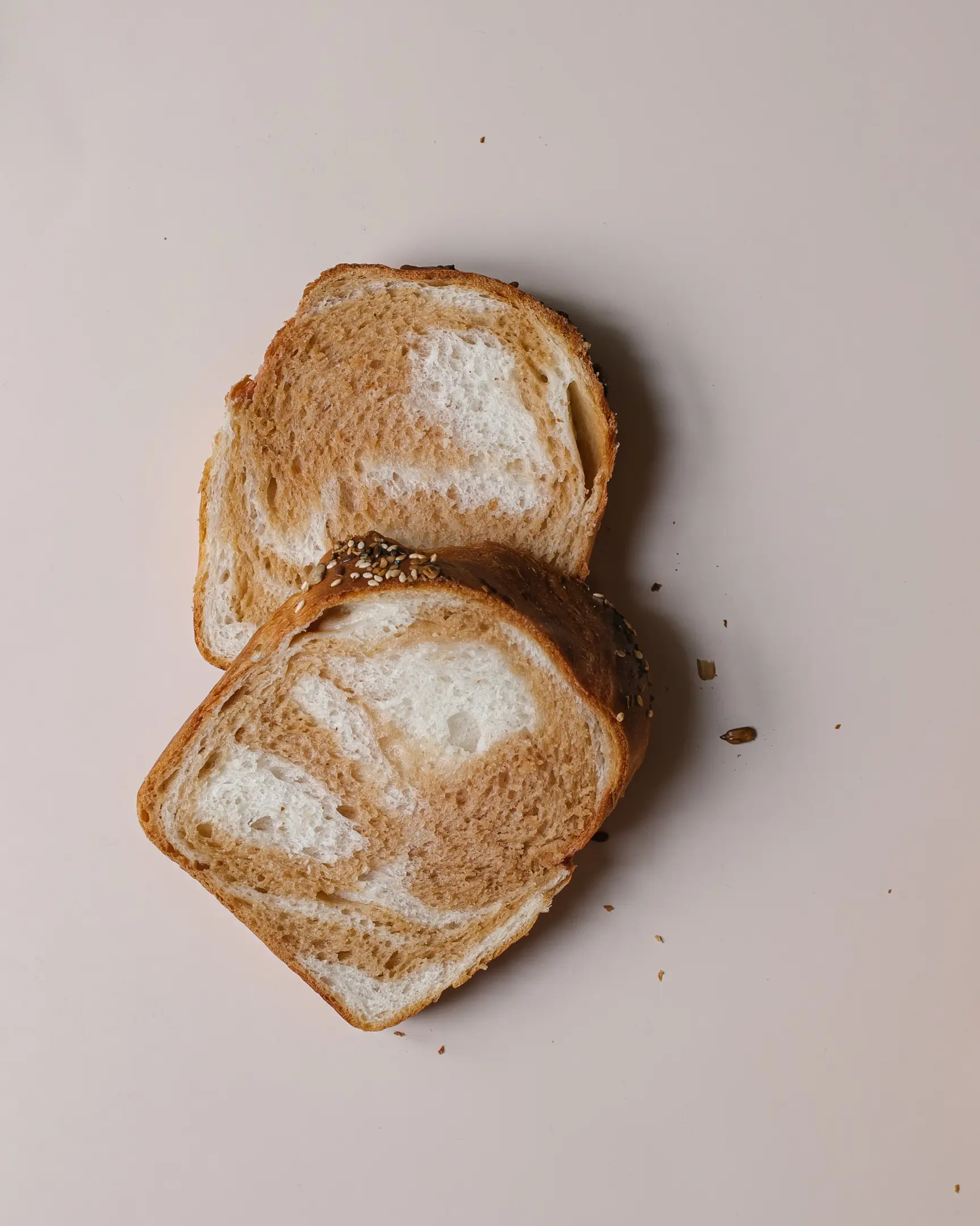 2 slices of bread lie on a light background.  2 slices of bread lie on a light background. They are cut. visible texture