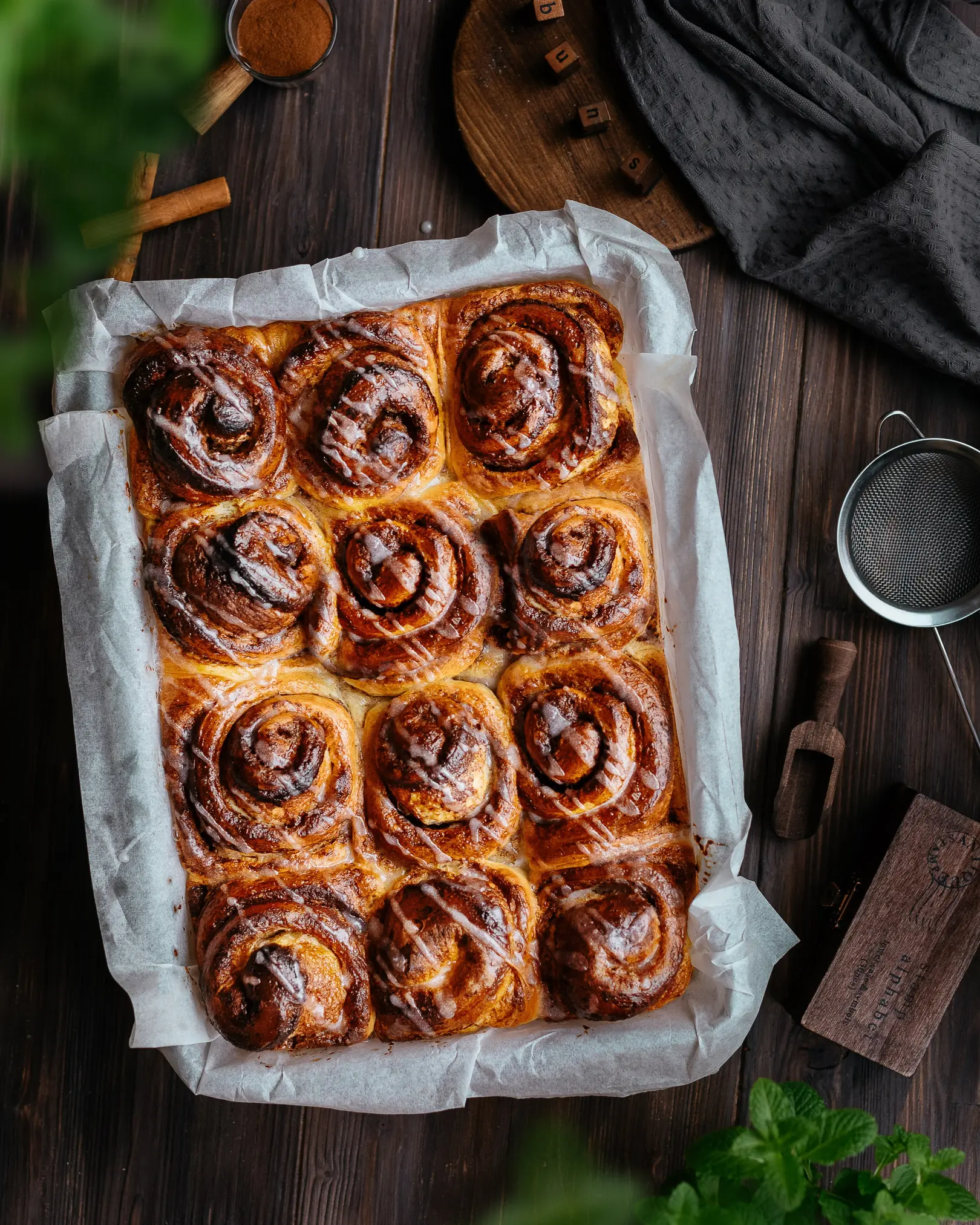 Buns on a wooden table. There is a glass form with buns on the table. The buns are covered with glaze-icing.