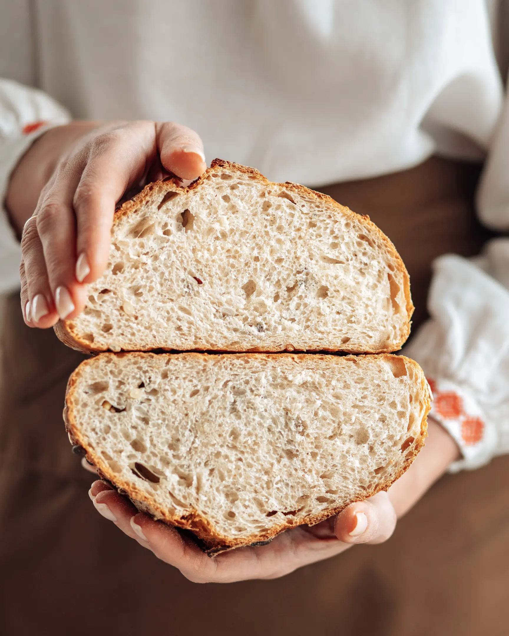 A woman holding cut bread in her hands. A woman holding the bread in her hands.