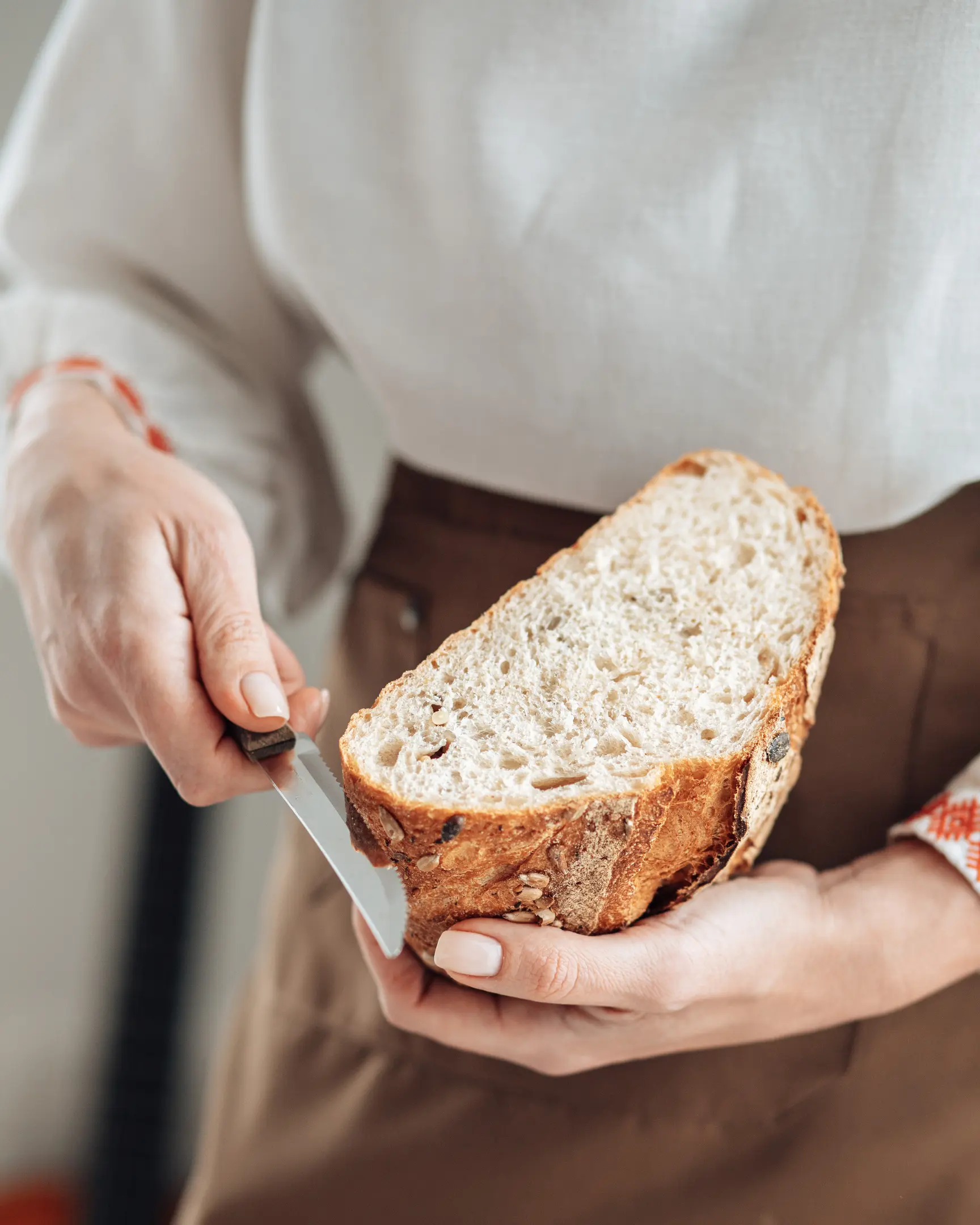 Жена реже с нож хляба в ръцете си. Жена реже с нож хляба в ръцете си.