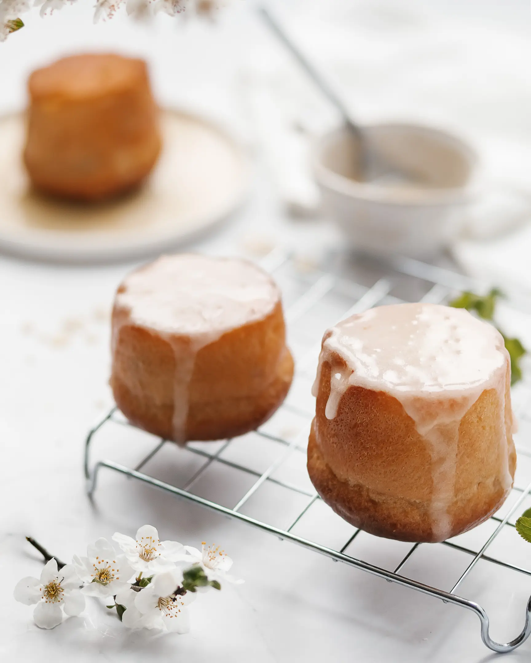 Rum babas lie on a confectionery grill for cooling. Rum babas lie on a confectionery grill for cooling. Flowers are visible in the foreground.