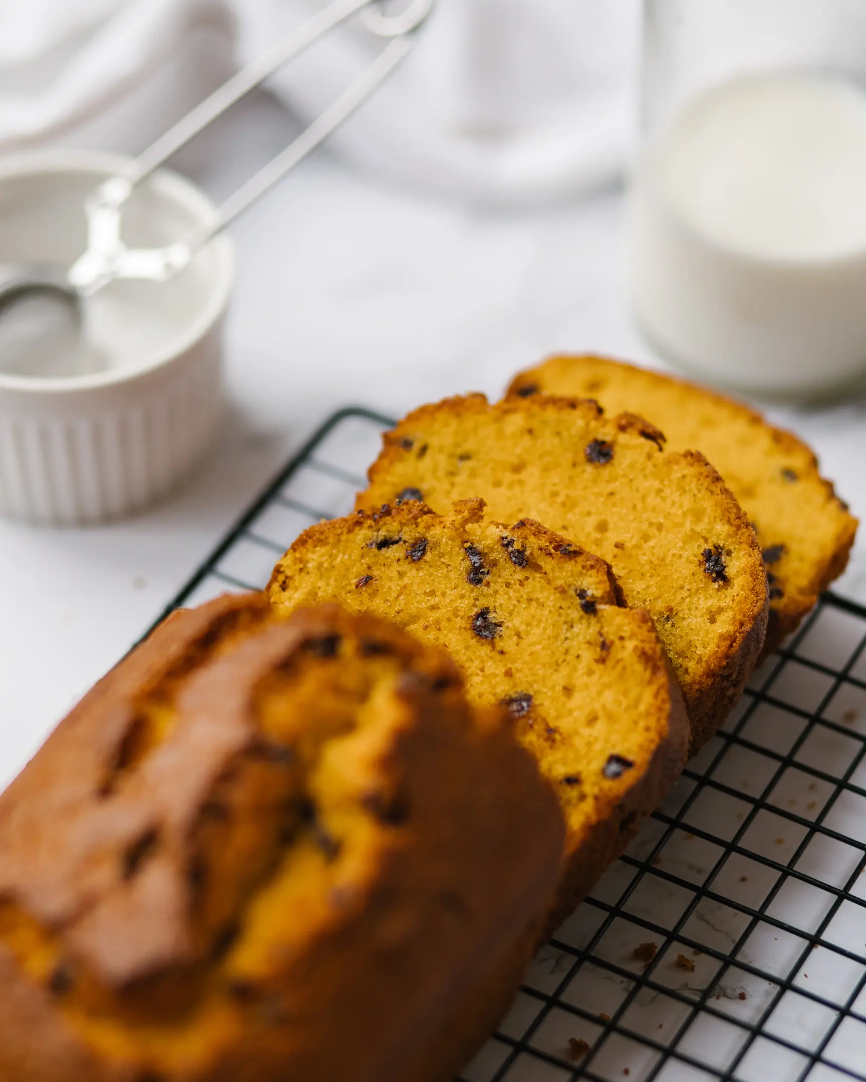 Carrot cake of bright yellow color cut. Carrot cake of bright yellow color cut. It has drops of chocolate in it. In the background is a plate of powdered sugar and a whisk for dusting the powder.