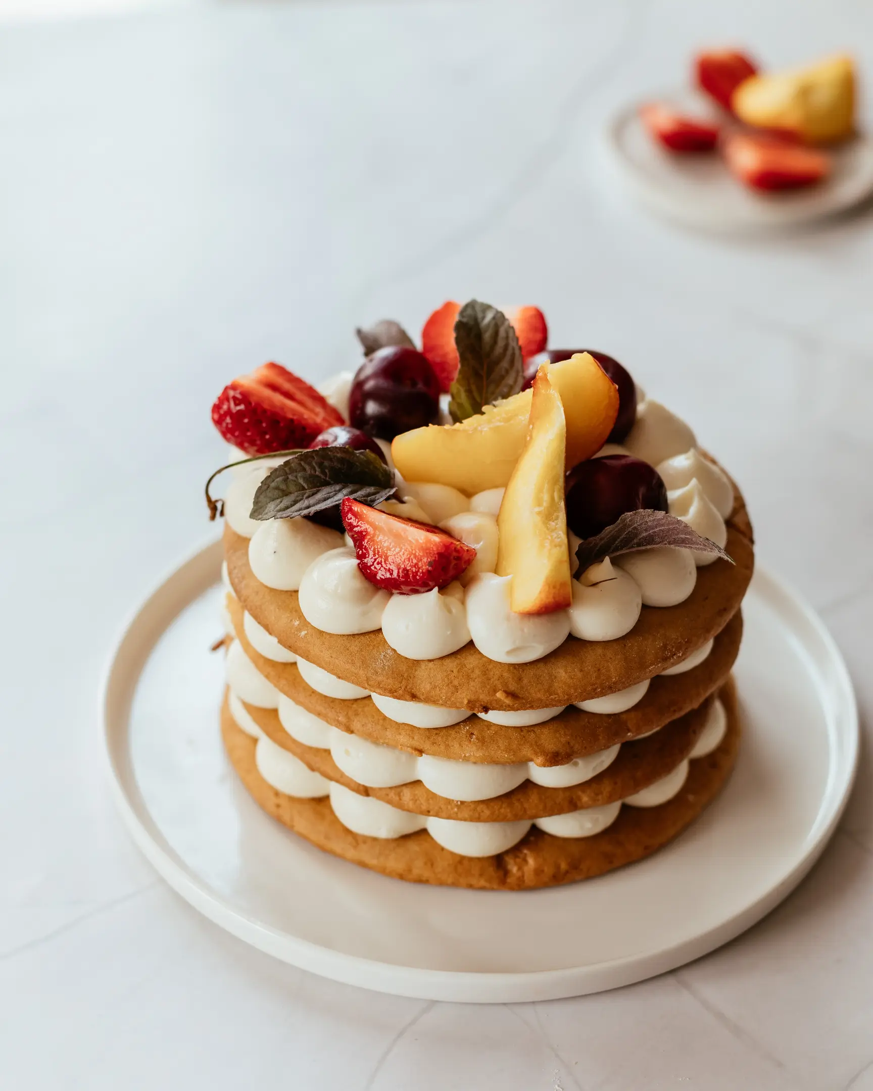 Слоеста медена торта, украсена с горски плодове, стои на маса. Слоеста медена торта, украсена с горски плодове, стои на маса.