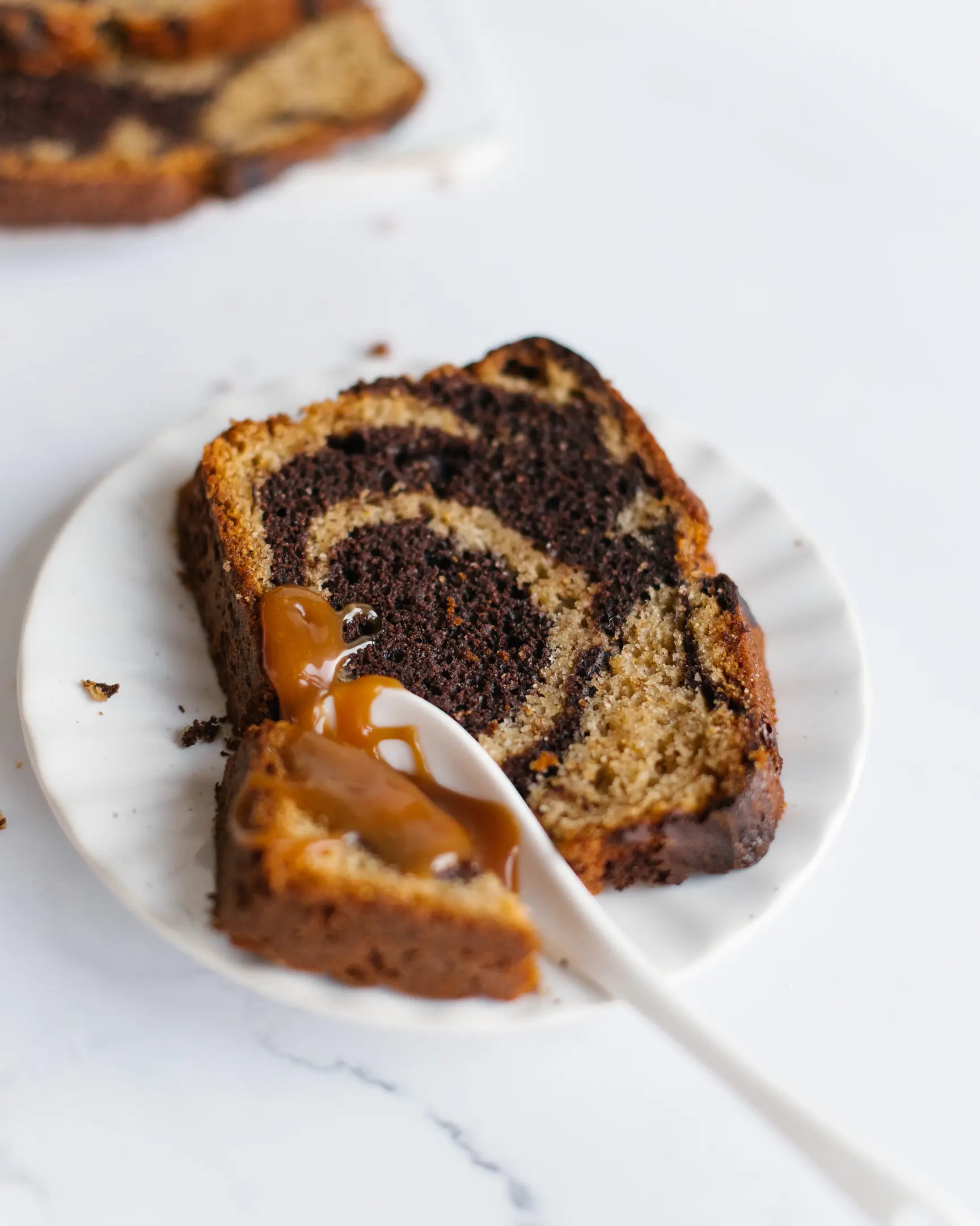 The cake is sliced. There is a sliced cake on a plate, it is poured with caramel. Someone has already begun to break it off with a spoon - to eat.