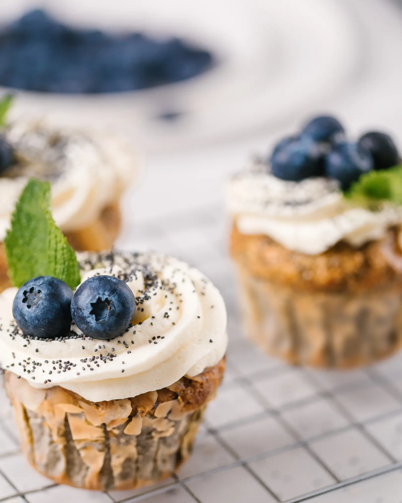 Orange poppy seed muffins (vegetarian) Orange poppy seed muffins are on a pastry rack to cool. They are decorated with cream caps and poppy seeds.