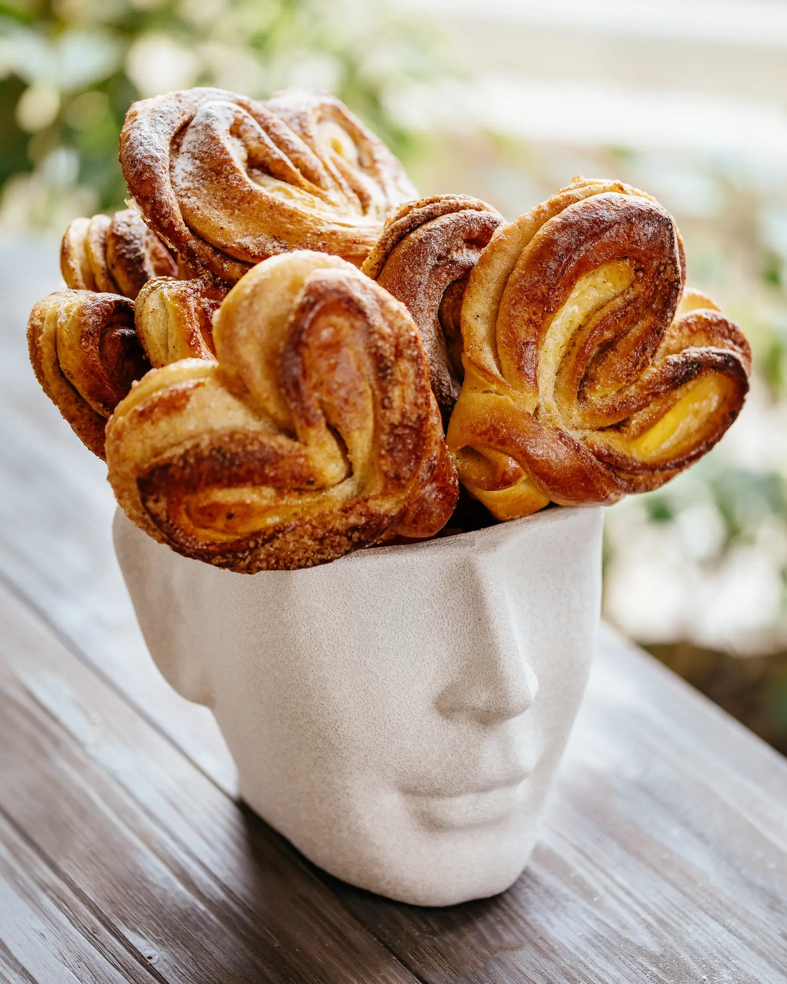 On a head-shaped plate are cinnamon rolls.  On a head-shaped plate are cinnamon rolls. The buns are made in the shape of hearts.