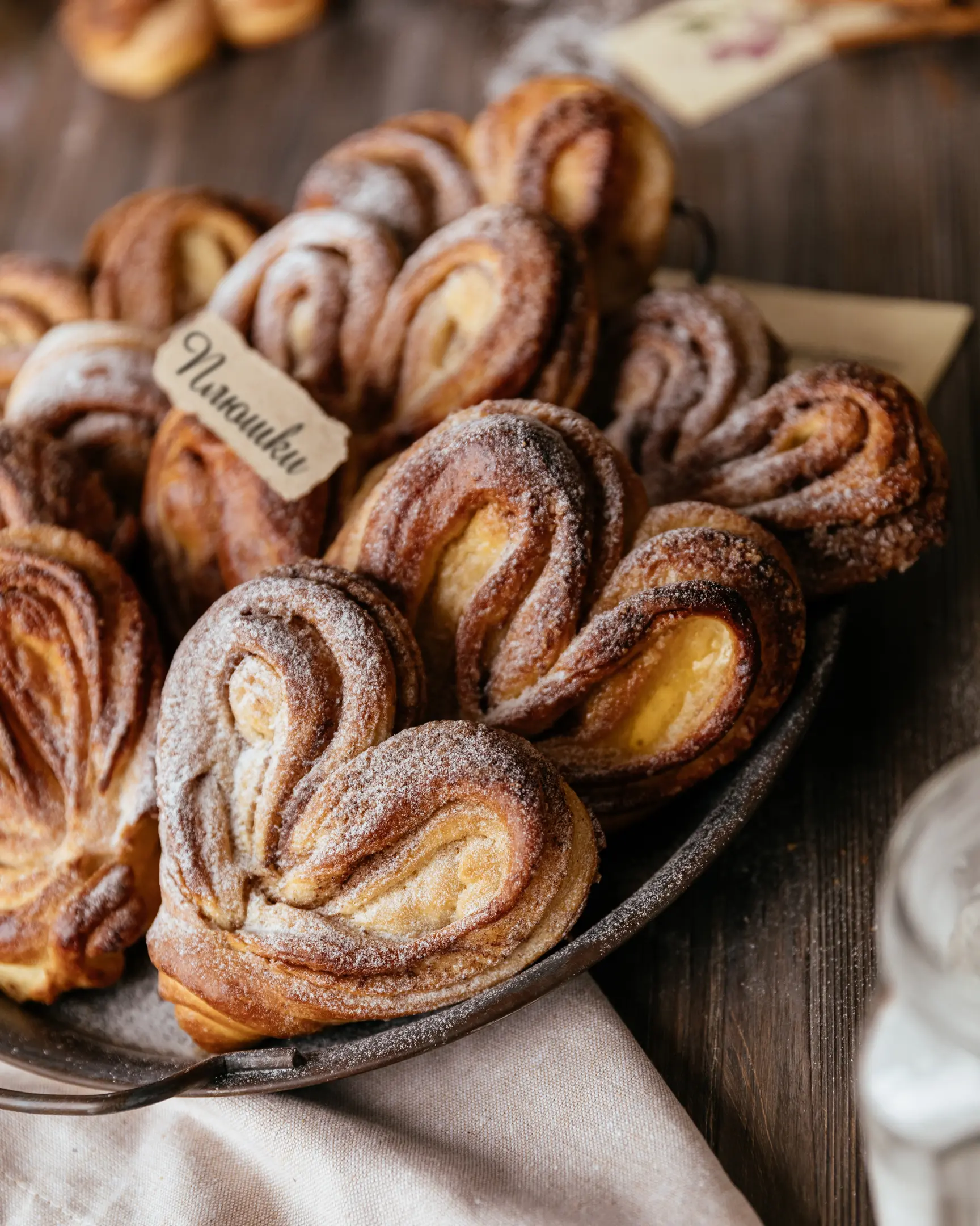 Heart-shaped buns lie on a wooden table Heart-shaped buns lie on a wooden table on a large metal plate. Cinnamon Sugar Rolls.