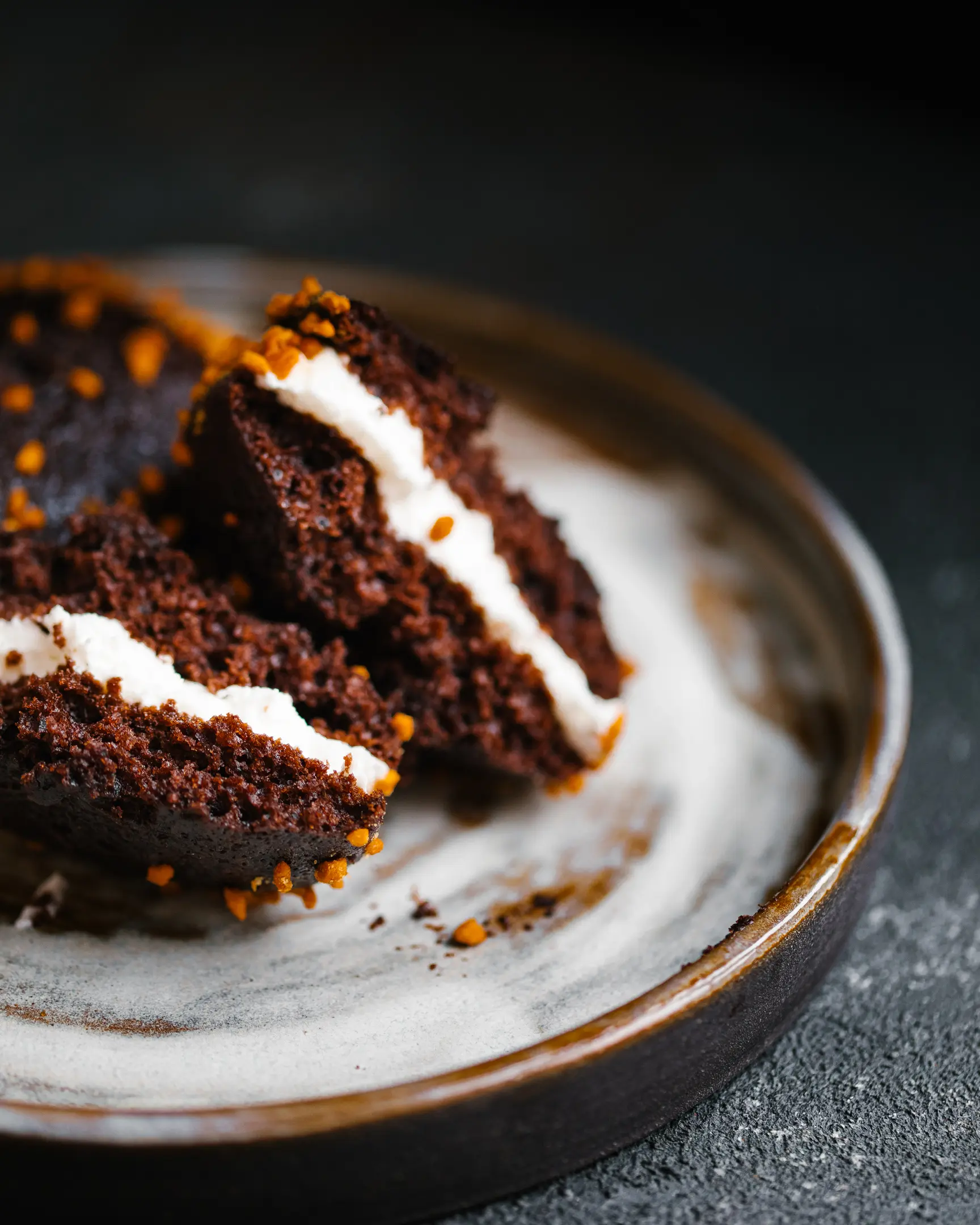 Cut chocolate whoopie-pies lie on a ceramic plate.  Chocolate whoopie-pies lie on a ceramic plate. They are layered with buttercream.