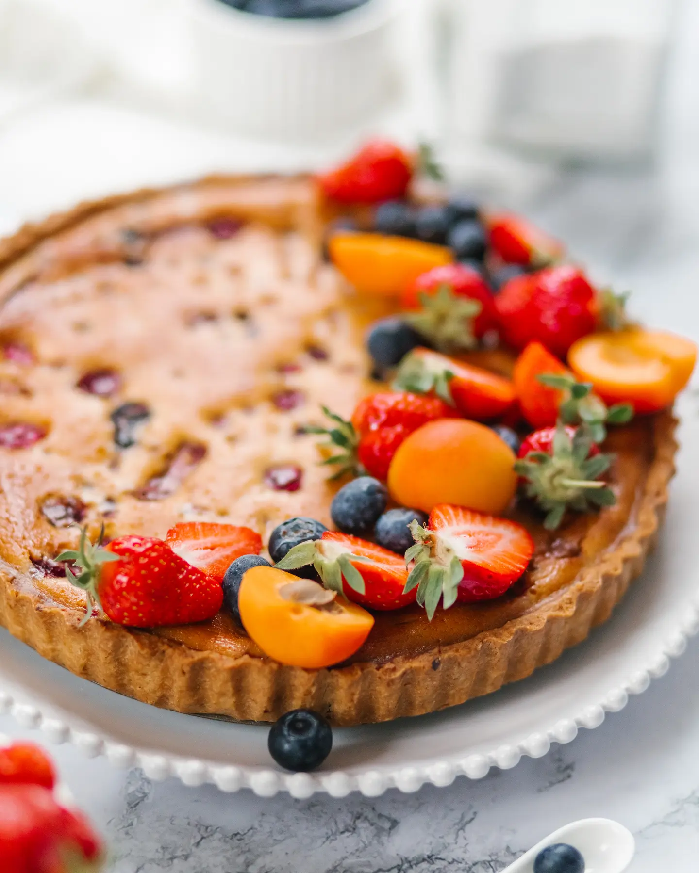 A round pie with berries is on the table. A round pie with berries is on the table. It has a golden brown crust. The pie is decorated with berries.