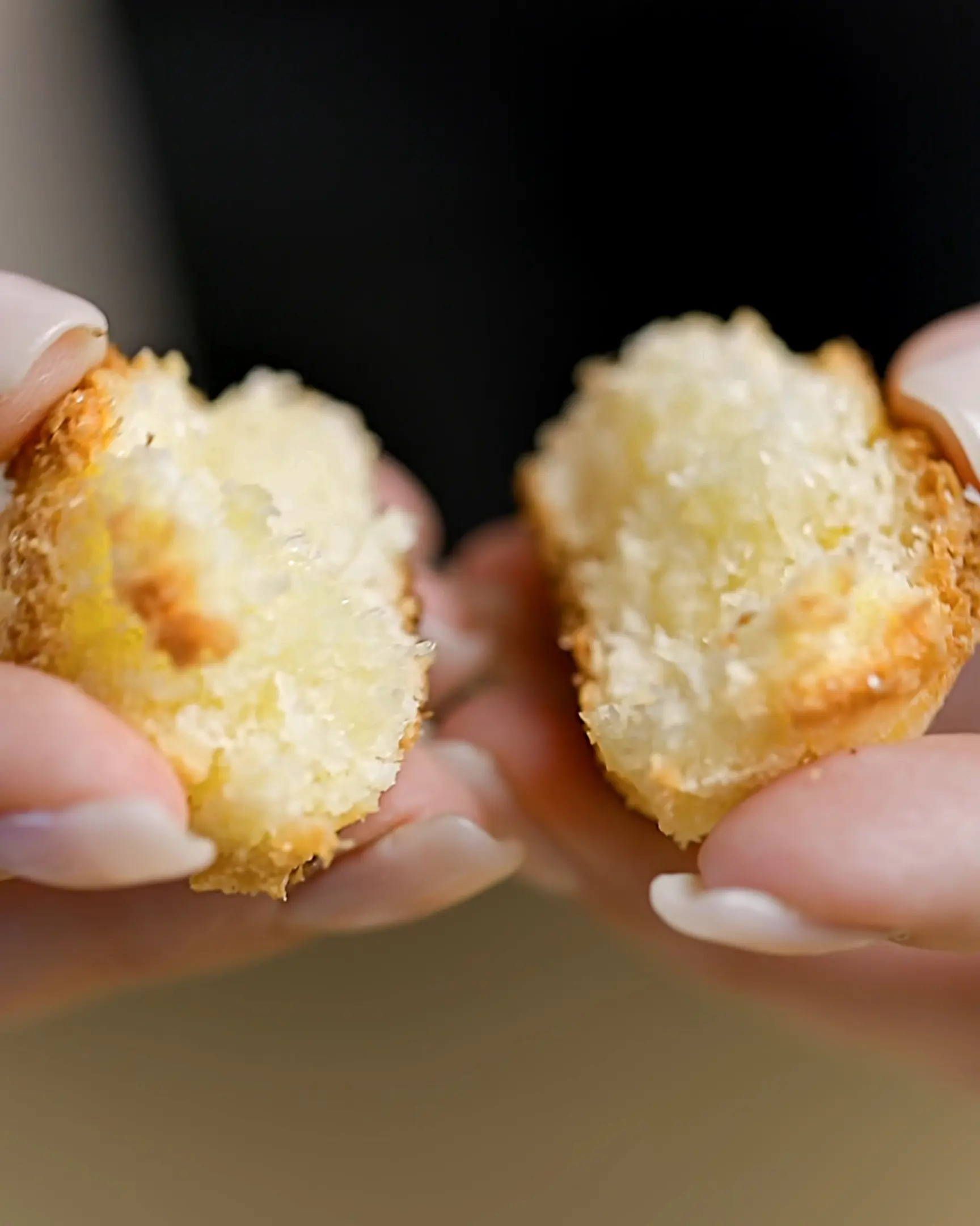The woman holds in her fingers a coconut cookie.  The woman holds in her fingers a coconut cookie. Showing the texture of cookie