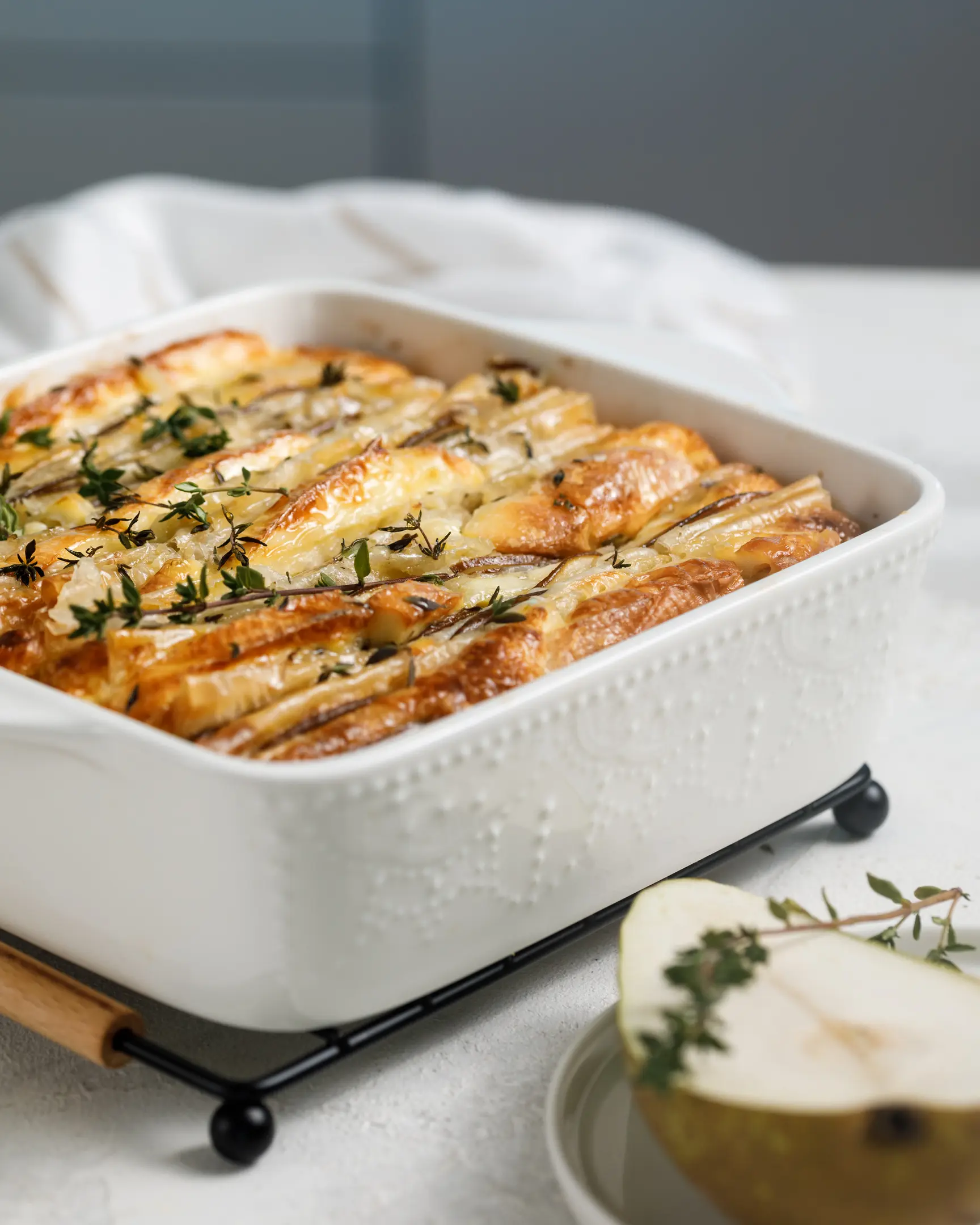 Ready tart with cheese and pears standing on the table. Ready tart with cheese and pears standing on the table. It is decorated with thyme. The viewers can see the golden crust of it.