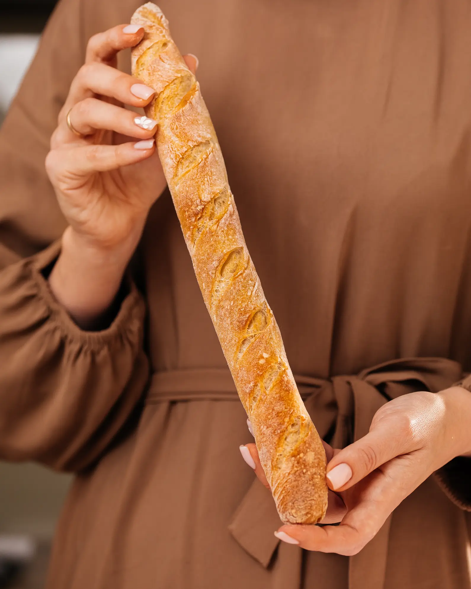 A woman in a beige dress holds a baguette in her hands A woman in a beige dress holds a baguette in her hands