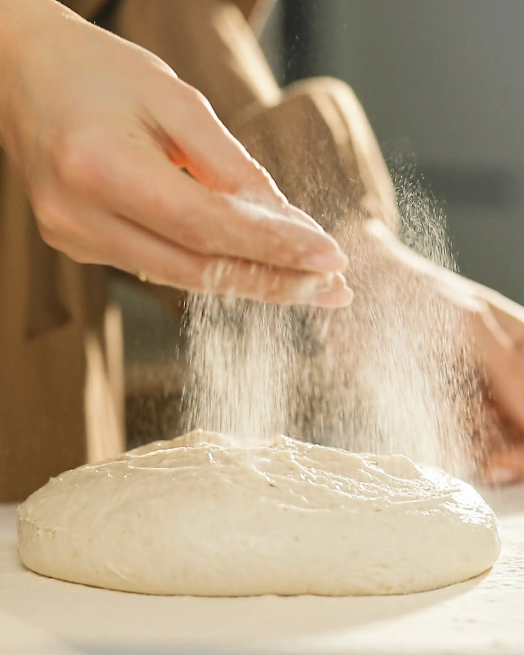 Woman sprinkles flour on baguette dough Woman sprinkles flour on baguette dough