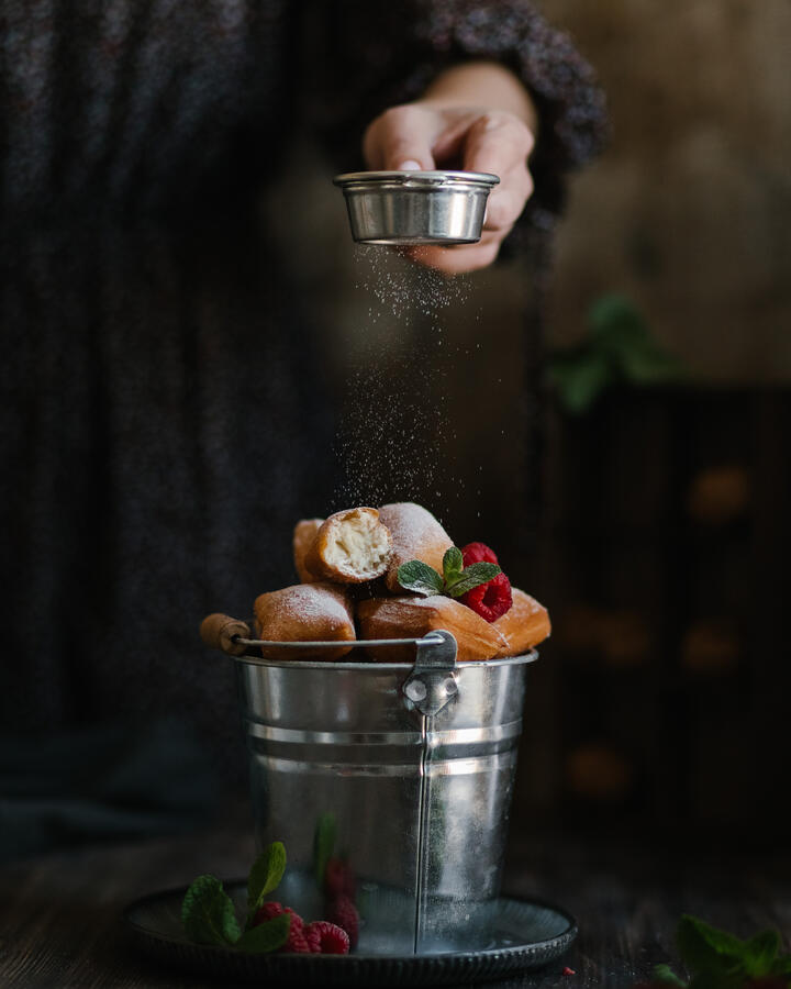 Woman sprinkles sugar icing on buns. Woman sprinkles sugar icing on buns.