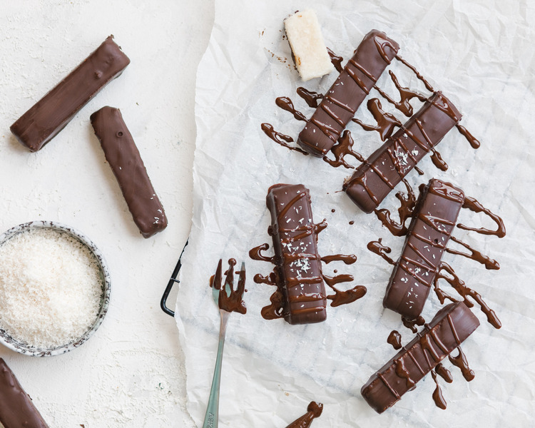 Chocolate bars topped with liquid chocolate. Seven chocolate bars are topped with liquid chocolate in the center of the photo with a white background.