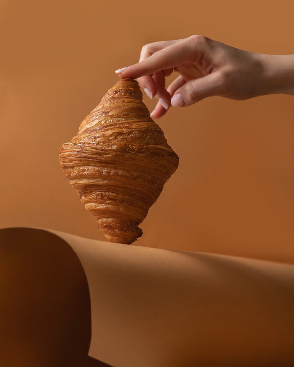 Croissant Savi Gelato. A person is holding a french croissant in the middle of the photo.