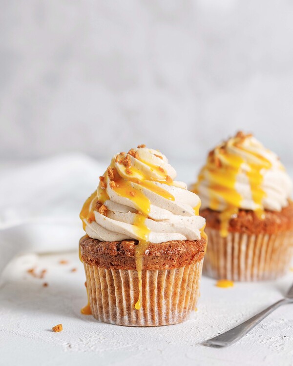 Cupcakes. A cupcake topped with rich hazelnut cream is in the middle of the picture. There is another one, the same, in the background. Both are topped with a cream made of mango.