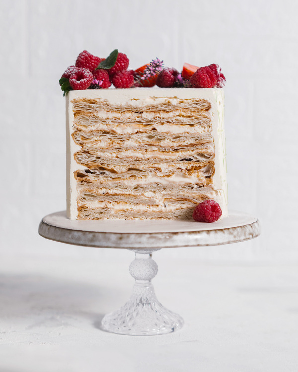 Napoleon Cake. Napoleon Cake. In the middle of the photo, there is a Napoleon Cake on a pedestal made of glass. On the top of it, there are raspberry and mint. You can see every layer of the cake!