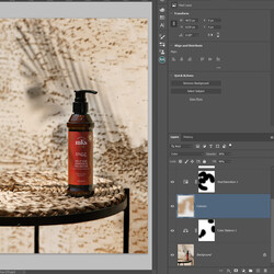 Retouching. A photographer uses an Adobe Photoshop application to adjust a photo of a bottle of serum (or shampoo). It is on a table and a shadow of a palm leaf behind it.