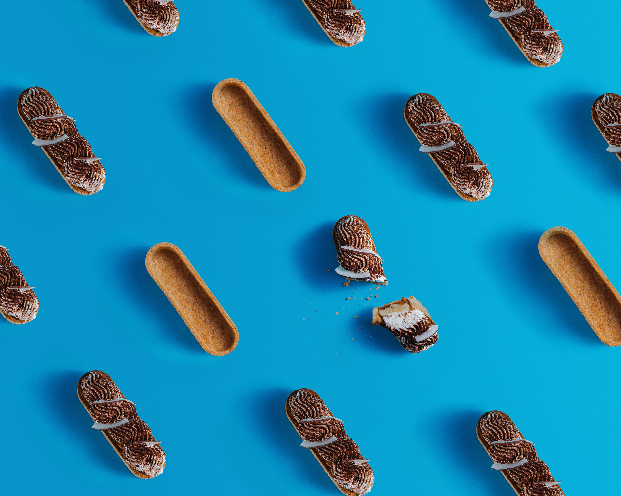 A pattern made of eclairs. On a blue background, some eclairs form a pattern.