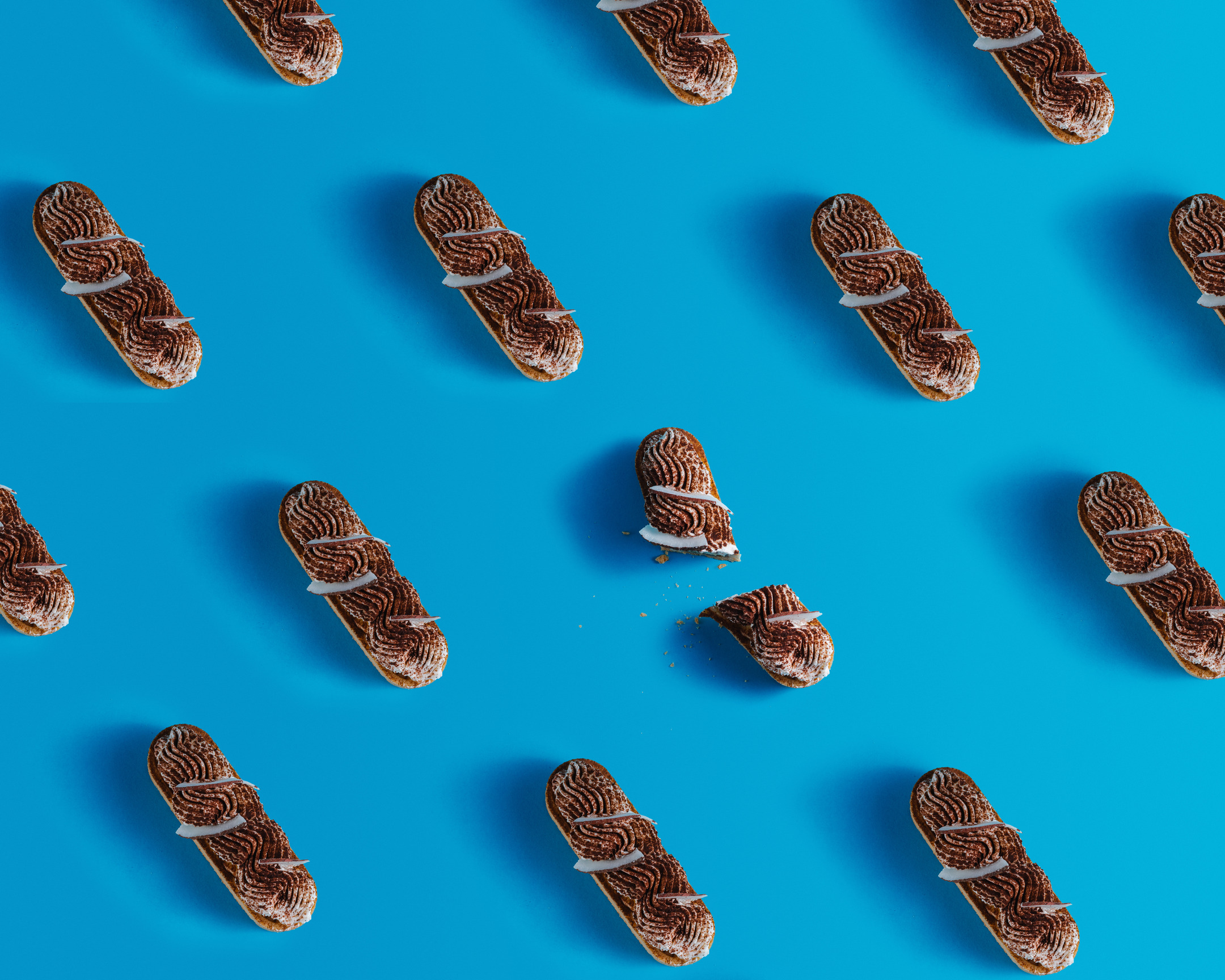 A pattern made of eclairs. On a blue background, some eclairs form a pattern.