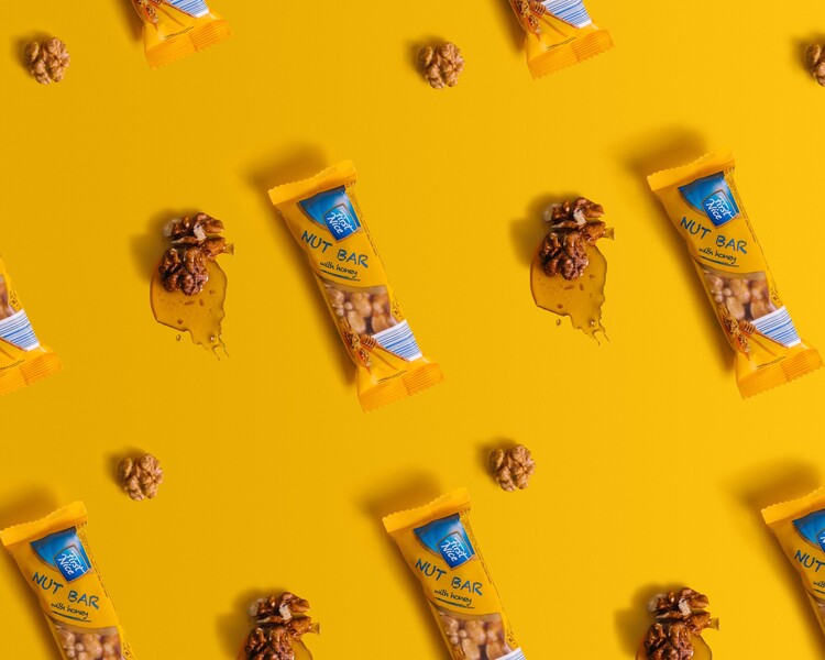 A pattern made of nut bars, honey, and walnuts. On a yellow background, nut bars, together with honey and walnuts, form a pattern.