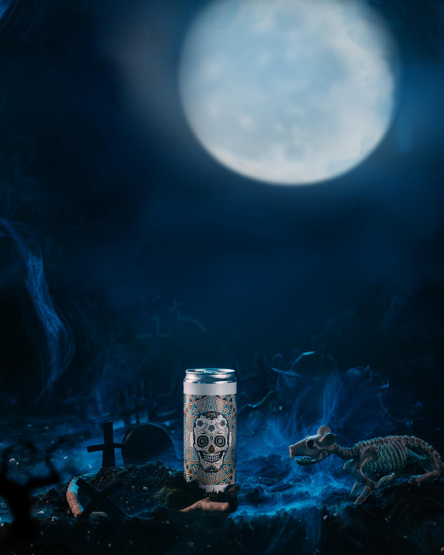 A beer-Bastard bottle stands in the foreground in the light of the moon. Vertical shot. A bottle of beer. Bastard stands in the foreground in the light of the moon. Judging by the ground around the bottle and the fog, events unfold in the cemetery at night. This conjecture is confirmed by the outlines of the graves in the background. The light of the moon illuminates the skeleton of a rat on the right - which is sneaking toward the bottle. Halloween ad shot.