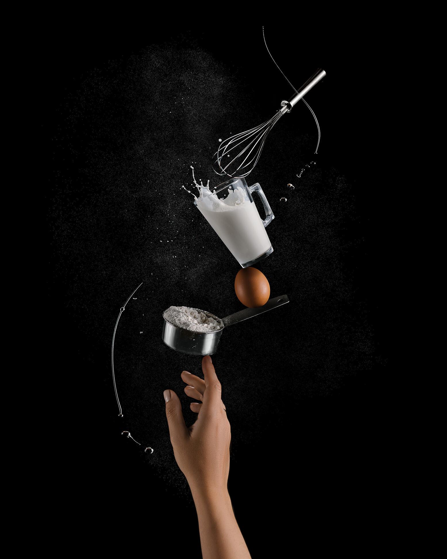 Ефектът на балансиращите продукти. Ефектът на балансиращите продукти. На снимката се вижда, че продуктите за приготвяне на палачинки са балансирани на 1 женски пръст. На пръста “стои” купа с брашно, върху нея везна яйце, а на върха на яйцето има чаша мляко, от което се излива съдържанието. Съставът се допълва от бъркалка, която стои на ръба на чаша мляко. Брашнен прах и зехтин летят около тази композиция.
