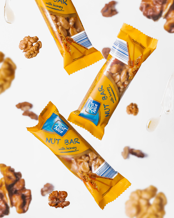 First Nice Nut bar in free fall flies among nuts and honey. First Nice Nut bar in free fall flies among nuts and honey. First Nice Nut bar on a light background in free fall flies among nuts and honey.
