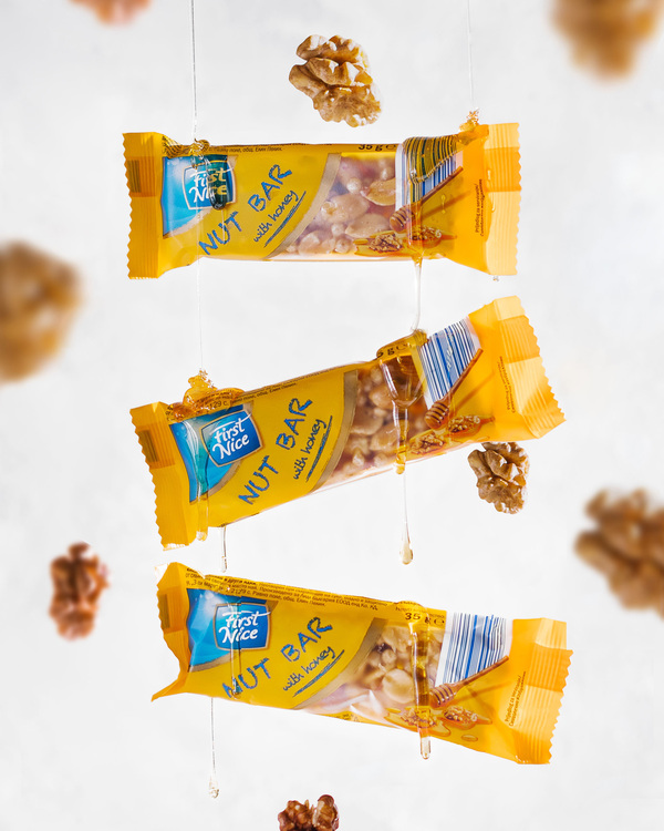 First Nice three nut bars in free fall flies among nuts and honey. First Nice three nut bars in free fall flies among nuts and honey. First Nice Nut bar on a light background in free fall flies among nuts and honey.Thin streams of honey flow down the bars
