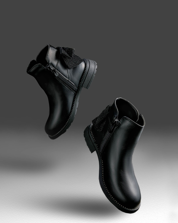 Flying Boots Flying Boots On a dark background, black boots for a girl float in the air. The boots have a bow with sequins.