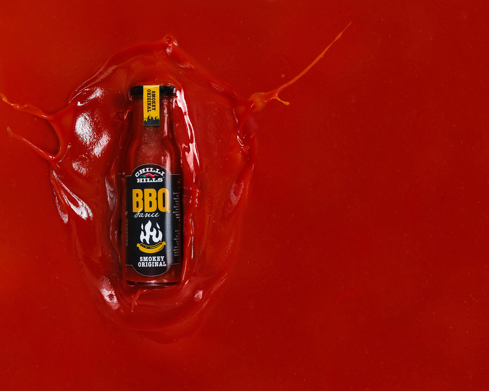 Ketchup BBQ Chilli Hills Bottle And ketchup Splash. The illusion that a jar of ketchup BBQ Chilli Hills falls into the ketchup container and this creates a splash.